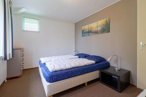 A bedroom with a bed, a nightstand, a lamp, a radiator, a window with blinds, and a painting on the wall. - Elegant Waterfront Bungalow with Jetty (Makkum)