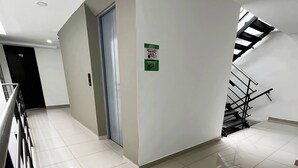 Un couloir propre et moderne, avec une rambarde en métal, une porte et un escalier doté d’une rambarde noire.