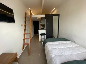 A compact bedroom with a bed, a wooden ladder, a desk, and a television. - VIP Nomad Nest in New PH with Air C, Kitchen, steps to Metroplus (Medellín)