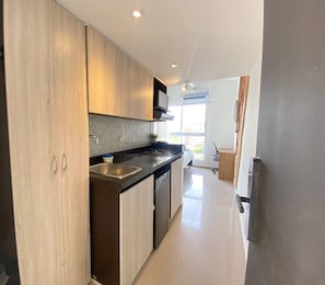 A modern kitchen with wooden cabinets, a black countertop, and a built-in stove. - VIP Nomad Nest in New PH with Air C, Kitchen, steps to Metroplus (Medellín)