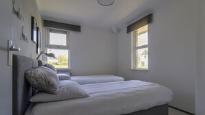 Ein Schlafzimmer mit zwei Betten, einem Fenster und einer Wandlampe.