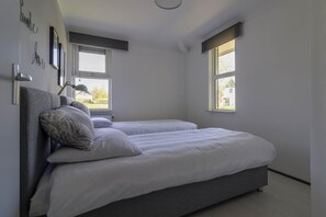 A bedroom with two beds, a window, and a wall-mounted lamp. - Makkum Bungalow with Private Jetty (Makkum)