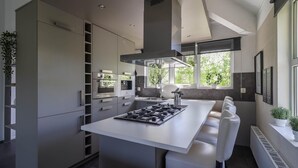 Eine moderne Küche mit einer zentralen Kochinsel, integrierten Geräten und einem großen Fenster.