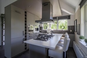 A modern kitchen with a central island, built-in appliances, and a large window. - Makkum Bungalow with Private Jetty (Makkum)