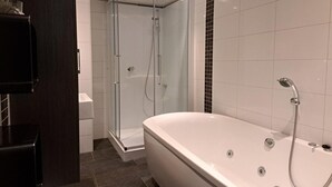 Ein modernes Badezimmer mit einer gläsernen Duschkabine, einer freistehenden Badewanne und weißen Fliesen.