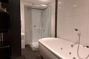 A modern bathroom with a glass-enclosed shower, a freestanding bathtub, and white tiled walls. - Makkum Bungalow with Private Jetty (Makkum)