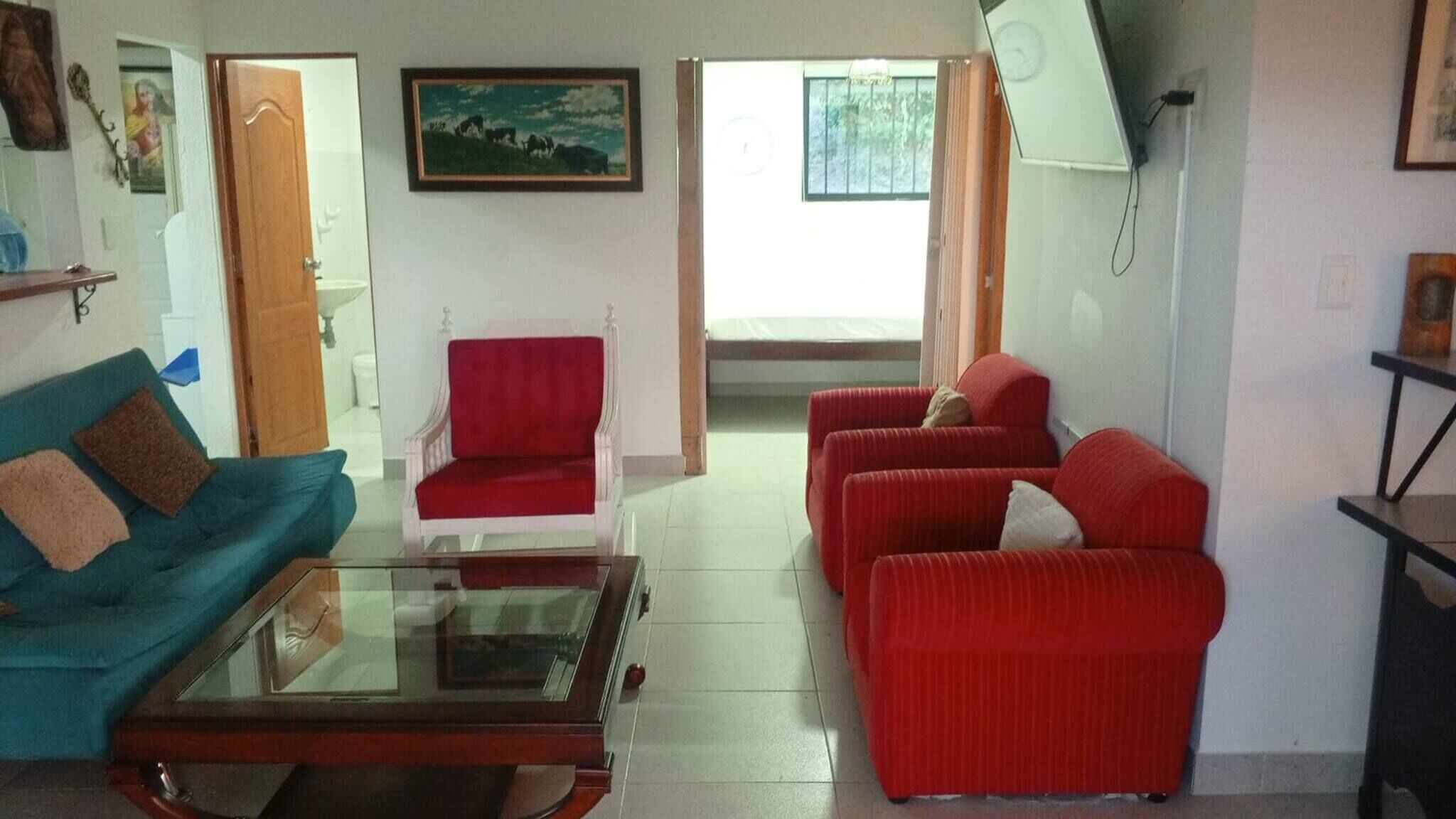 A living room with a sofa, armchair, and a glass coffee table.