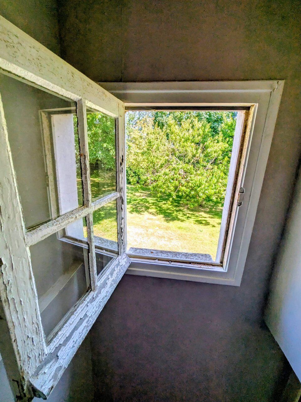 Een kamer met een raam dat uitzicht biedt op een tuin.