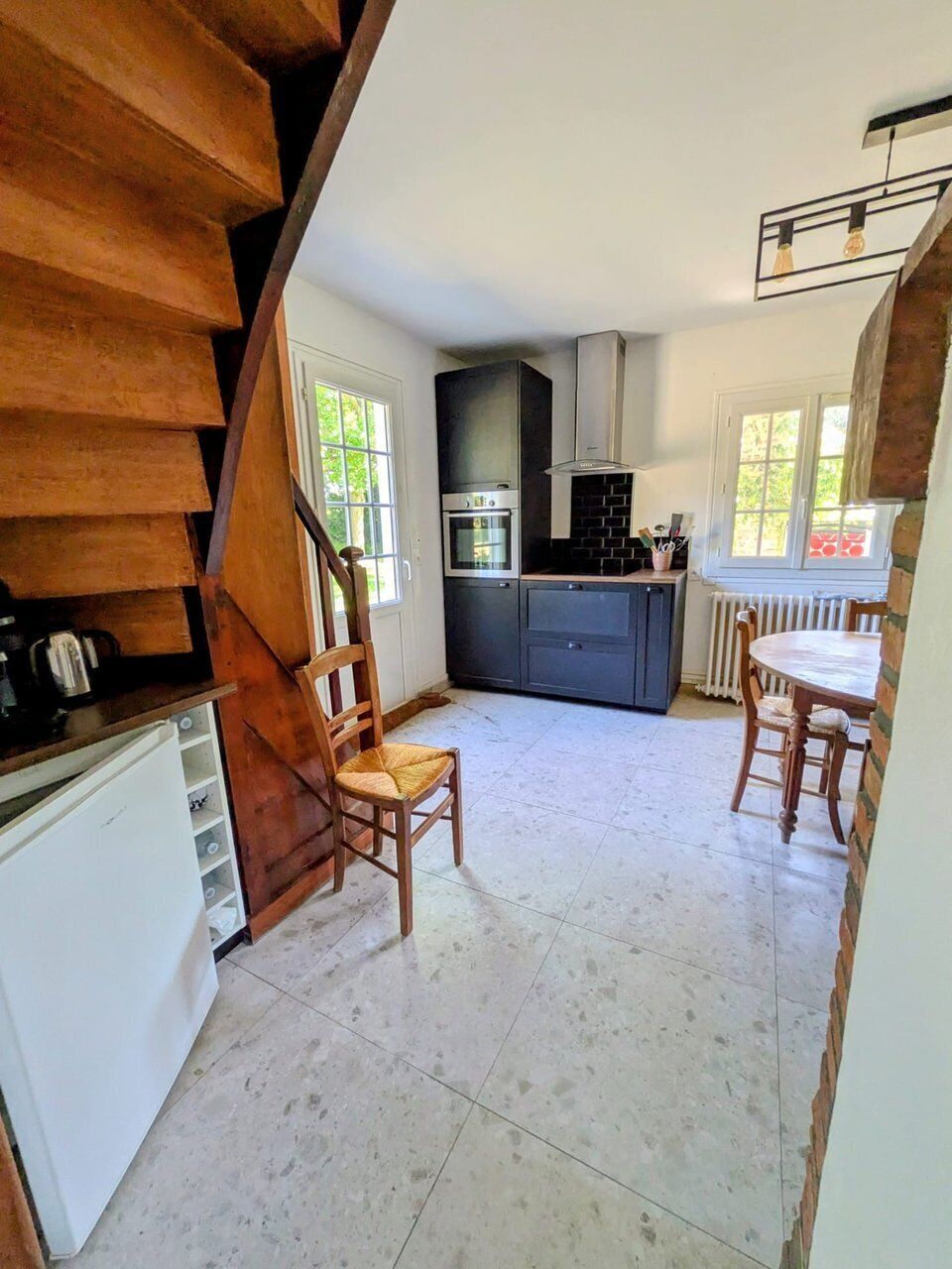 Una cocina con una isla central, armarios blancos y una escalera de madera.
