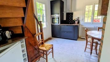 Una cocina con una isla central, armarios blancos y una escalera de madera.