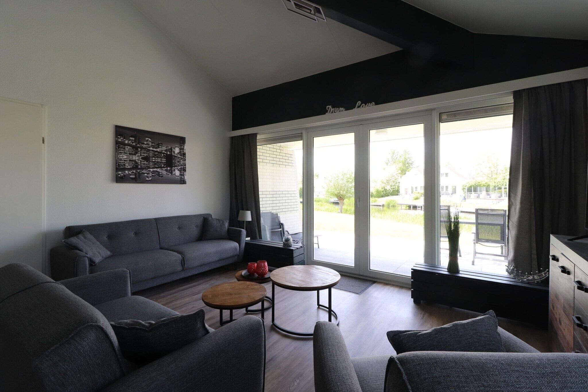 Una sala de estar moderna con un sofá gris, una mesa de centro redonda y una obra de arte con un paisaje urbano en la pared.