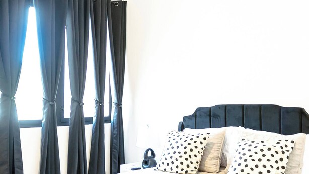 Ein Schlafzimmer mit Bett, Vorhängen, Deckenventilator und Fenster.