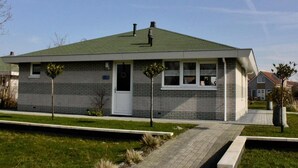 Ein eingeschossiges Haus mit Gründach, einer Haustür und zwei Fenstern.