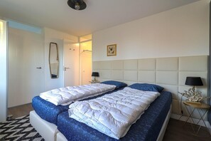 A double bed with white and blue bedding, a bedside table with a lamp, and a wall-mounted mirror. - Luxury 3BR Waterfront Villa (Makkum)