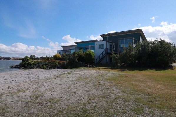 Une propriété située sur la côte, dotée d’une maison moderne, d’une plage de sable et offrant une vue dégagée sur la mer.