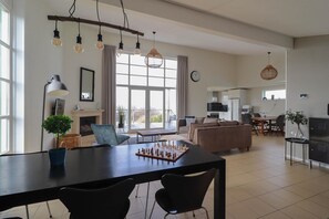 A spacious living area with a dining table, chairs, a sofa, and a chessboard. - Luxury Detached Villa near the Beach (Makkum)