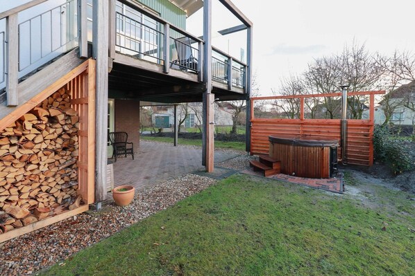 Een modern buitengebied met een houten terras, een jacuzzi en een overdekte zithoek.