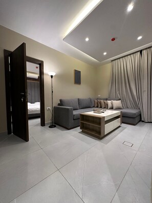 Ein modernes Wohnzimmer mit einem Sofa, einem Couchtisch und einer Tür zu einem Schlafzimmer.