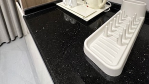 Et moderne køkken med en sort granitbordplade, kaffemaskine og elkedel på et fad.