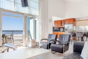 A modern living room with a balcony overlooking the sea, a kitchen with wooden cabinets, and a dining area with bar stools. - Luxury Makkum Beachvilla for 6 (Makkum)