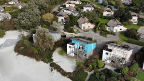 Zona residencial costera con casas, una playa y un pequeño edificio azul con una escalera.