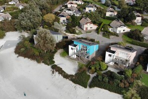 A coastal residential area with houses, a beach, and a small blue building with a staircase. - Luxury Makkum Beachvilla for 6 (Makkum)