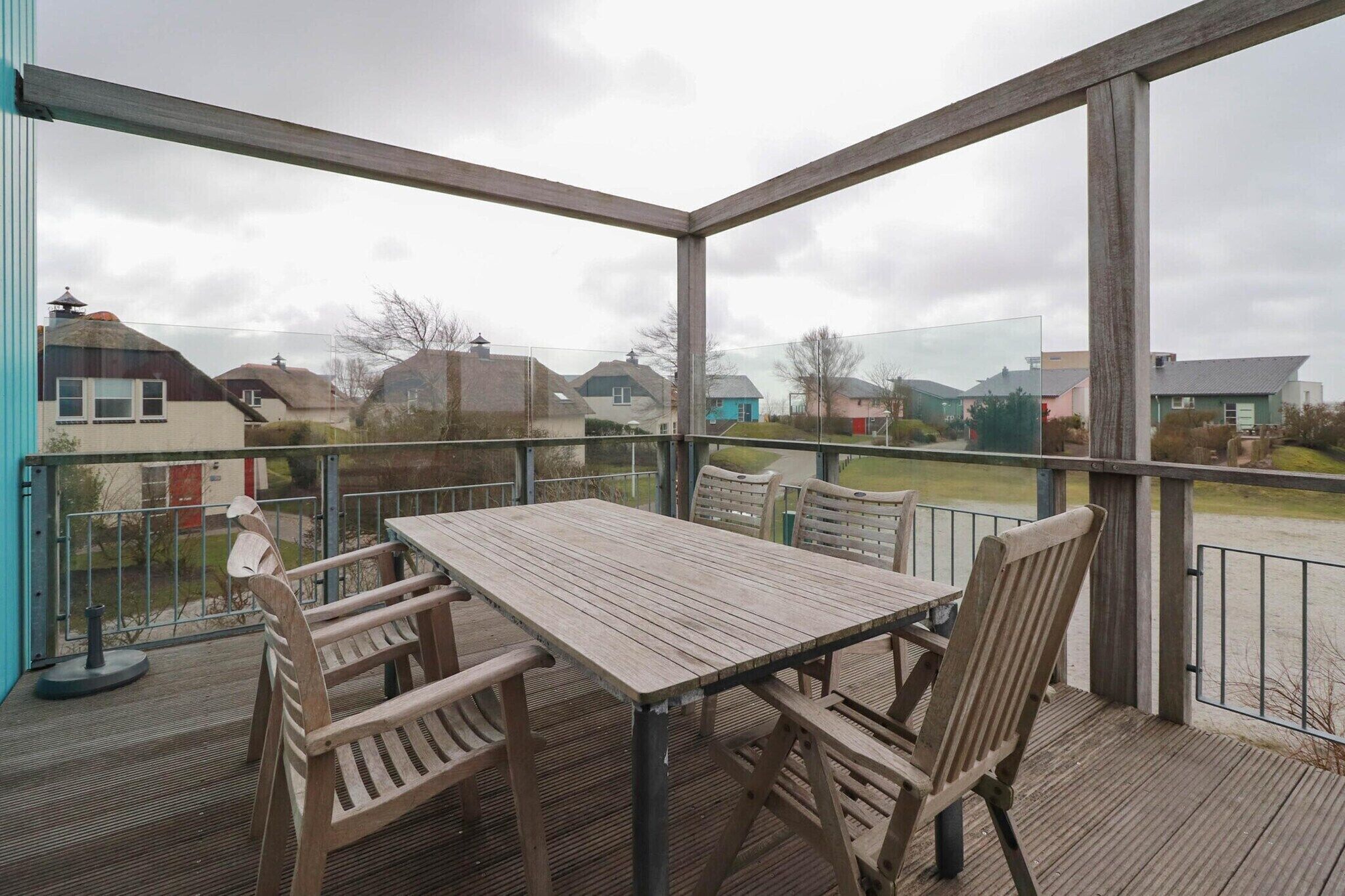 Un patio techado al aire libre con una mesa y sillas, con vista a una zona residencial.