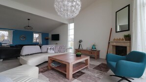 A modern living room with a sofa, coffee table, and a blue armchair. - Beach Villa with Sauna for 8 Guests (Makkum)