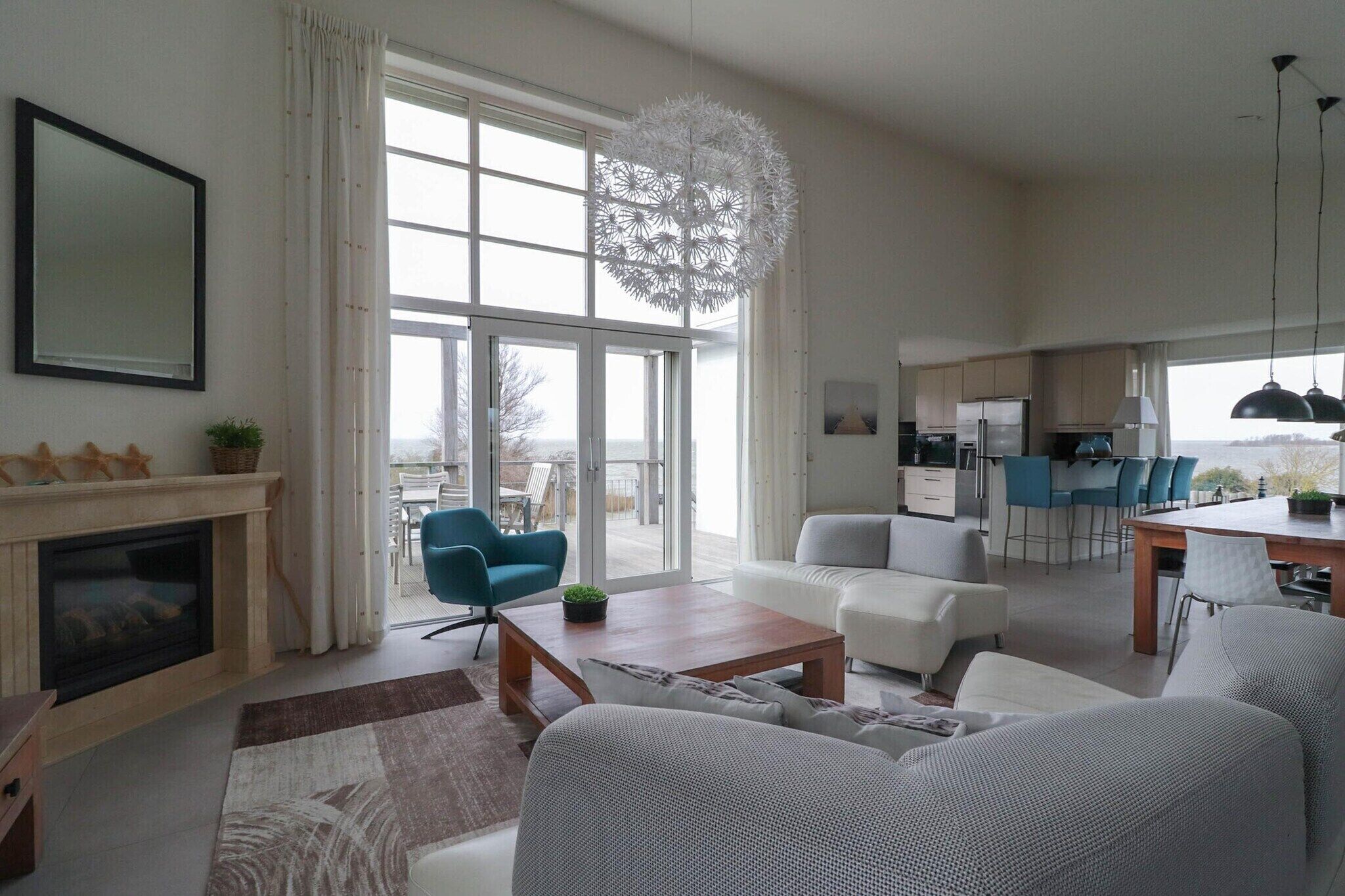 A modern living room with a fireplace, a dining area, and a kitchen.