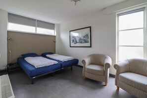 A room with two beds, a chair, a radiator, and a framed picture on the wall. - Beach Villa with Sauna for 8 Guests (Makkum)