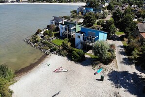 Une propriété située sur la côte, avec une plage, un petit bateau et un bâtiment à la façade bleue.