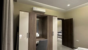 Ein Hotelzimmer mit einem Bett, einem Schreibtisch mit Stuhl, einem Kleiderschrank und einer Klimaanlage.
