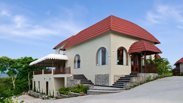 A two-story building with a red roof, multiple windows, and a stone staircase leading to the entrance. - Aamba Bagh Resort Kumbhalgarh  (Kumbhalgarh)