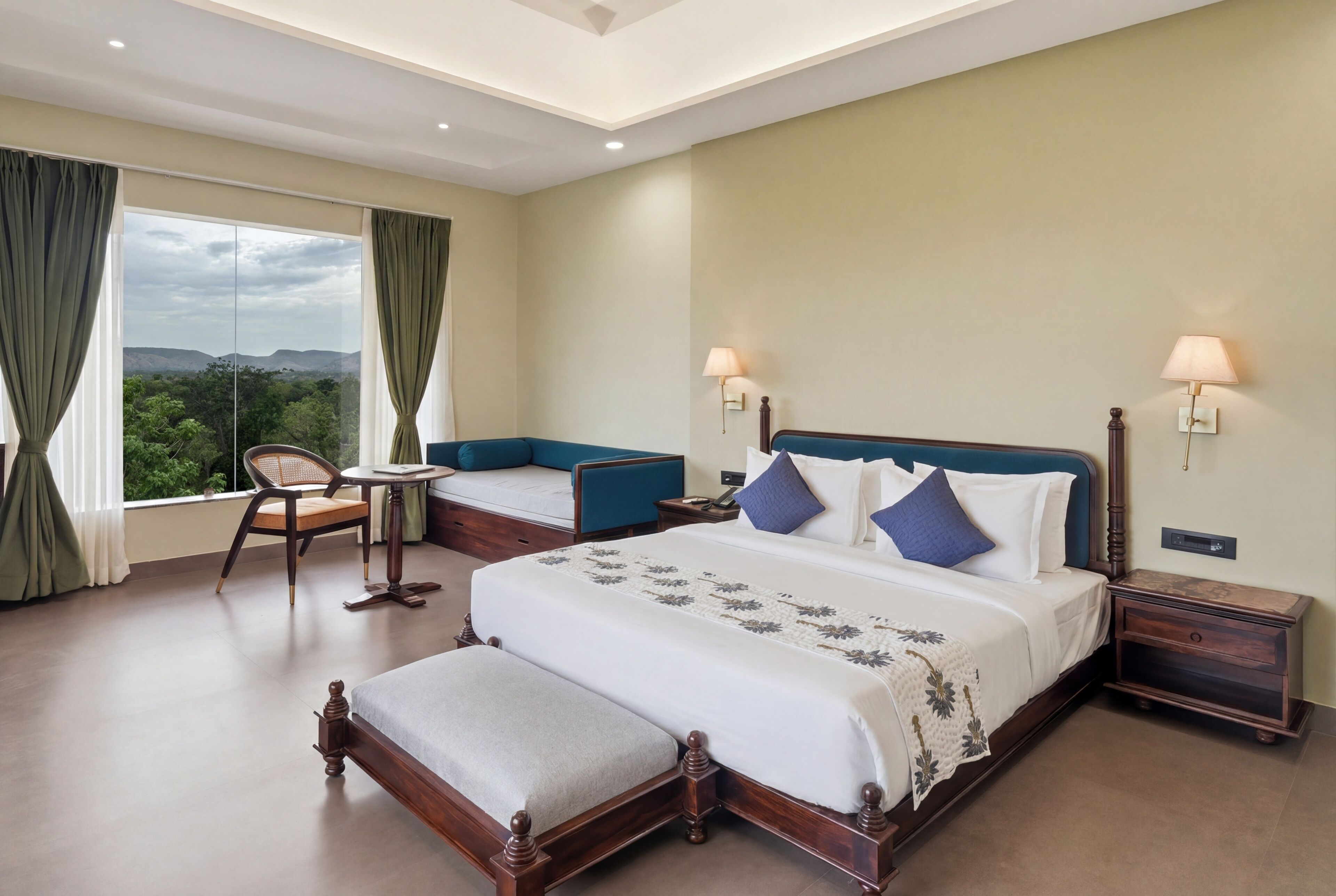 A hotel room with a large bed, a small table, a chair, and a view of the outdoors.