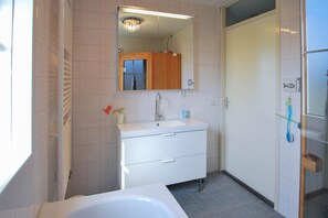 Ein Badezimmer mit einem weißen Waschbecken, einem Spiegel und einem Holzschrank.
