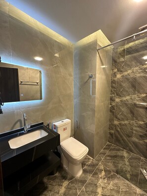 Ein modernes Badezimmer mit Marmorboden, einer weißen Toilette, einem schwarzen Waschbecken und einer Duschkabine aus Glas.