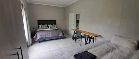 A bedroom with a bed, a desk, and a chair.