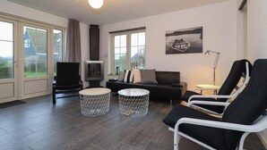 Ett modernt vardagsrum med en soffa, två fåtöljer, en tv och en öppen spis.