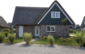 A single-story house with a dark roof, a brick facade, and a small front porch. - Beach Villa with Garden & Water Access (Makkum)
