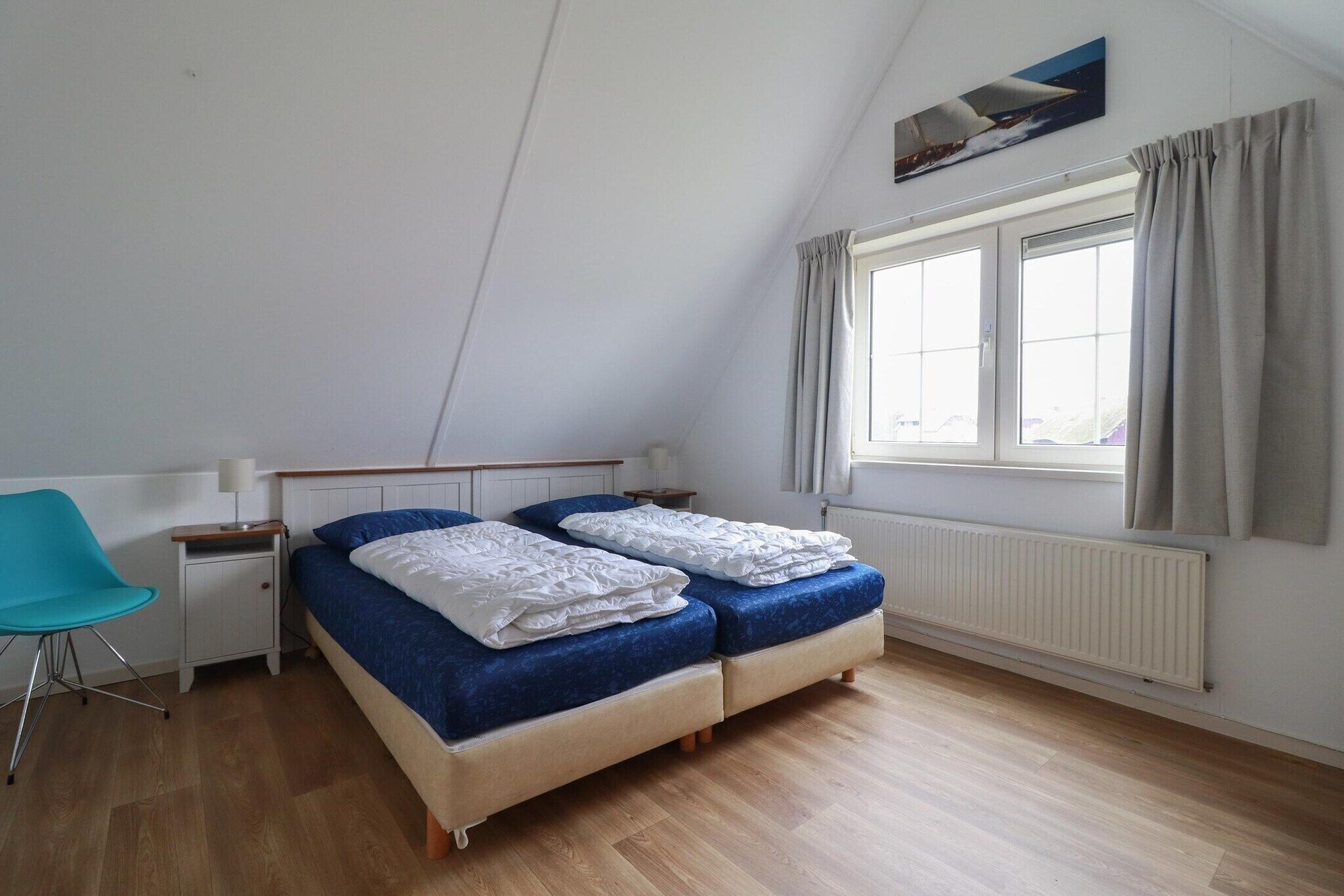 A bedroom with a bed, a chair, a window, and a radiator.