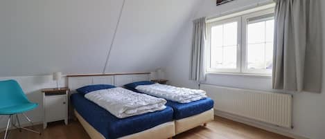 A bedroom with a bed, a chair, a window, and a radiator.