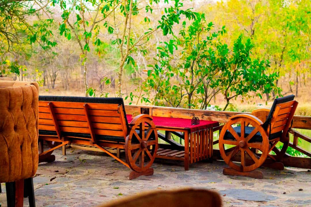 A wooden outdoor seating area with a table and chairs, surrounded by trees.