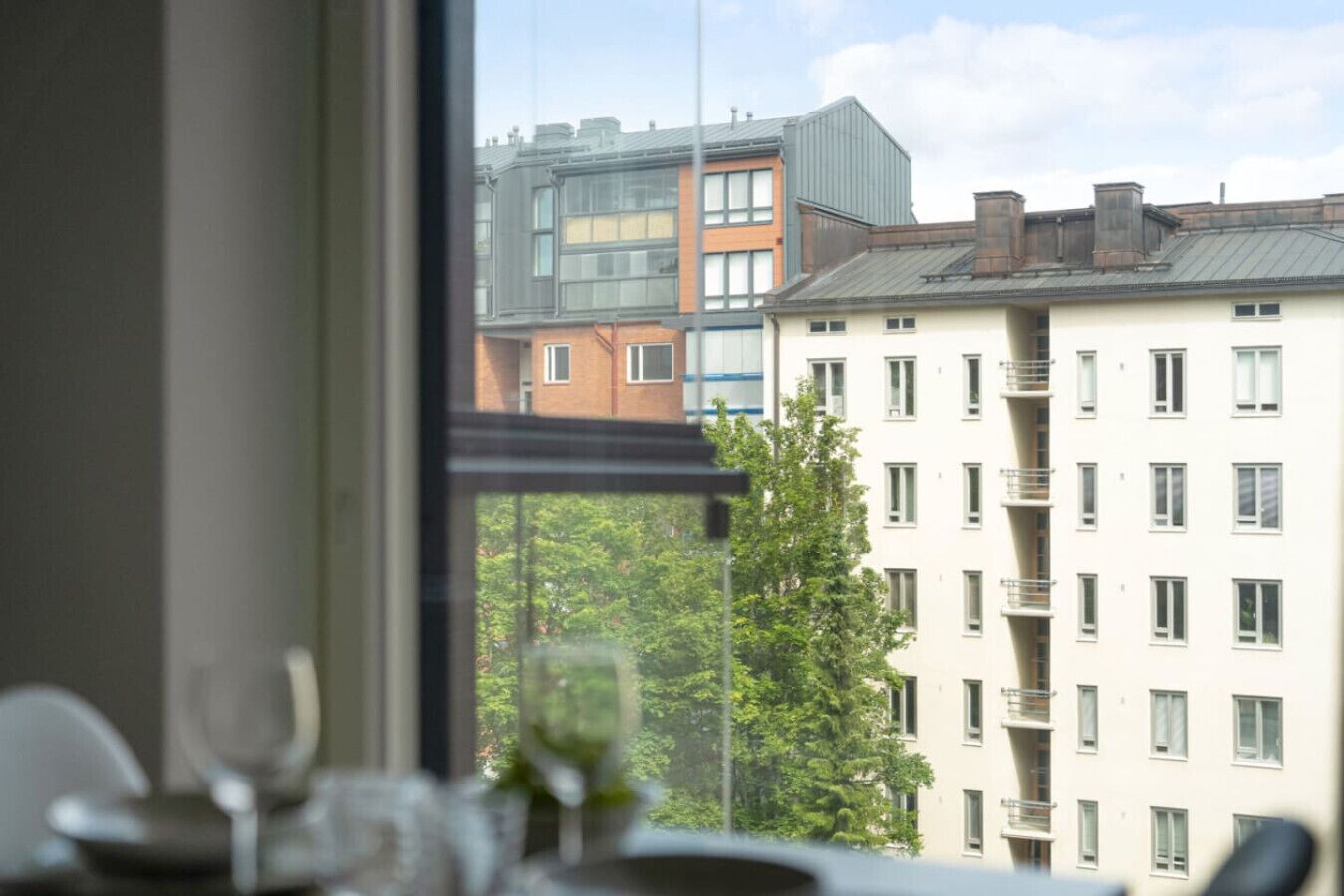 A view through a window of a building with multiple floors, balconies, and a mix of architectural styles.