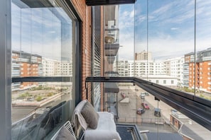 Een hoog appartementencomplex met uitzicht op omliggende gebouwen en een parkeerplaats beneden.