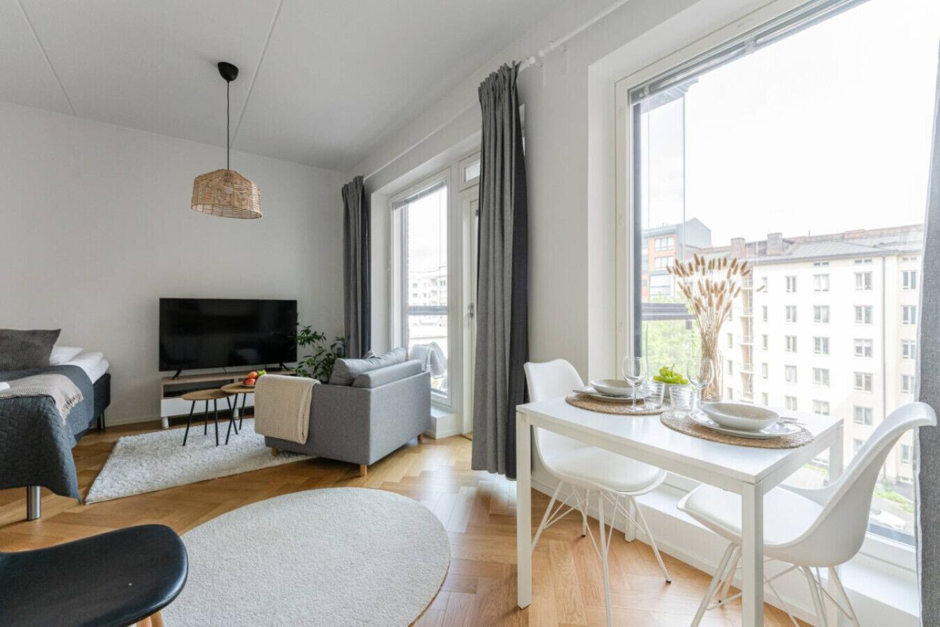 A modern living room with a sofa, TV, dining table, and chairs.