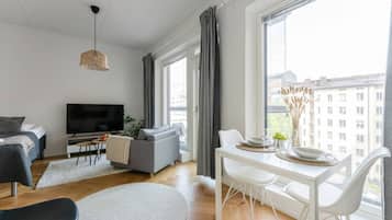 A modern living room with a sofa, TV, dining table, and chairs.
