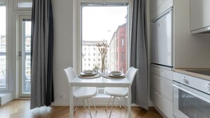 A modern kitchen with white cabinetry, a dining table with chairs, and a window with curtains.