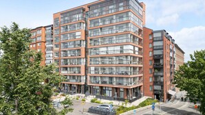 En flervåningsbostadsbyggnad med stora fönster, en fasad av tegel och ett platt tak.