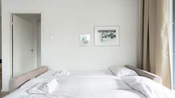 A hotel room with a bed, two pillows, a door, and two framed pictures on the wall.
