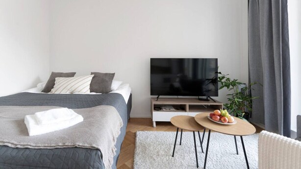 A modern bedroom with a bed, TV, and a small table with fruit.